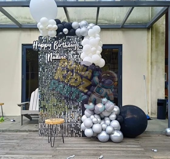 Silver sequin backdrop with balloon garland at a birthday party